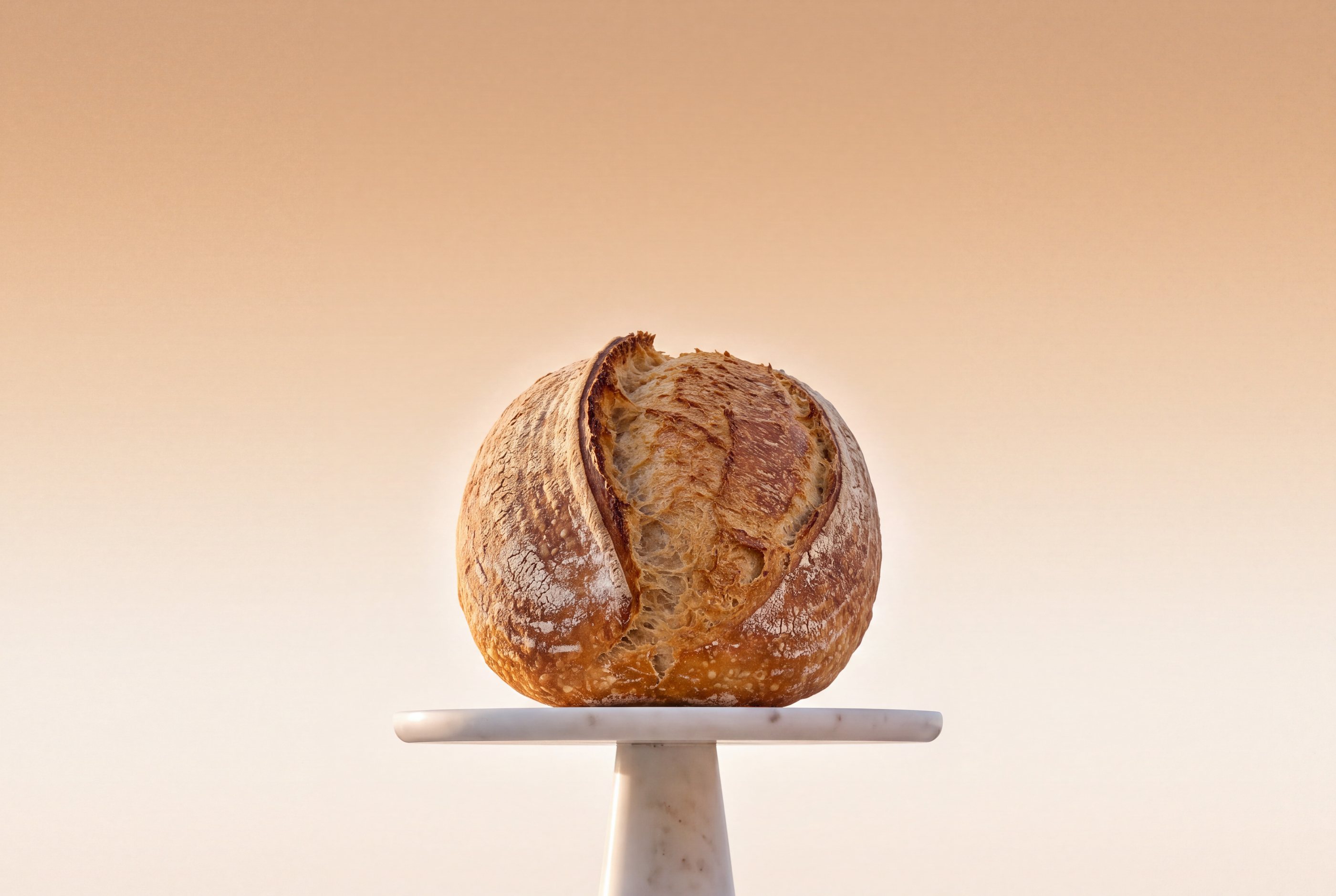 A sourdough boule on a small marble stand