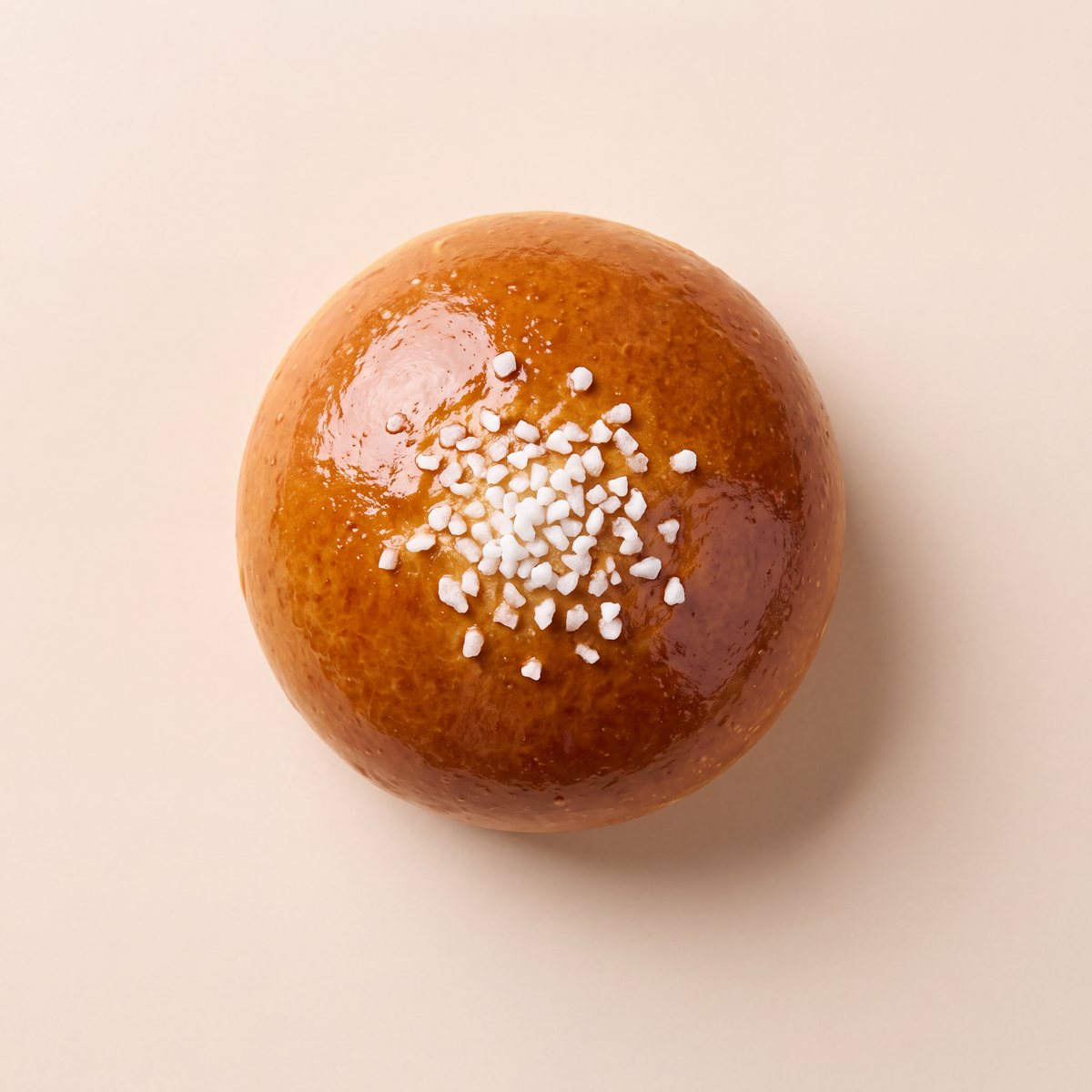 A glossy brioche bun with pearl sugar, seen from above